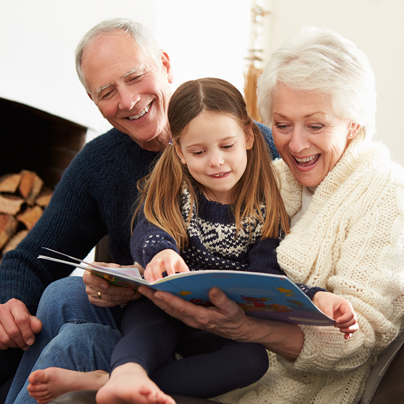 Grandparents reading book to granddaughter